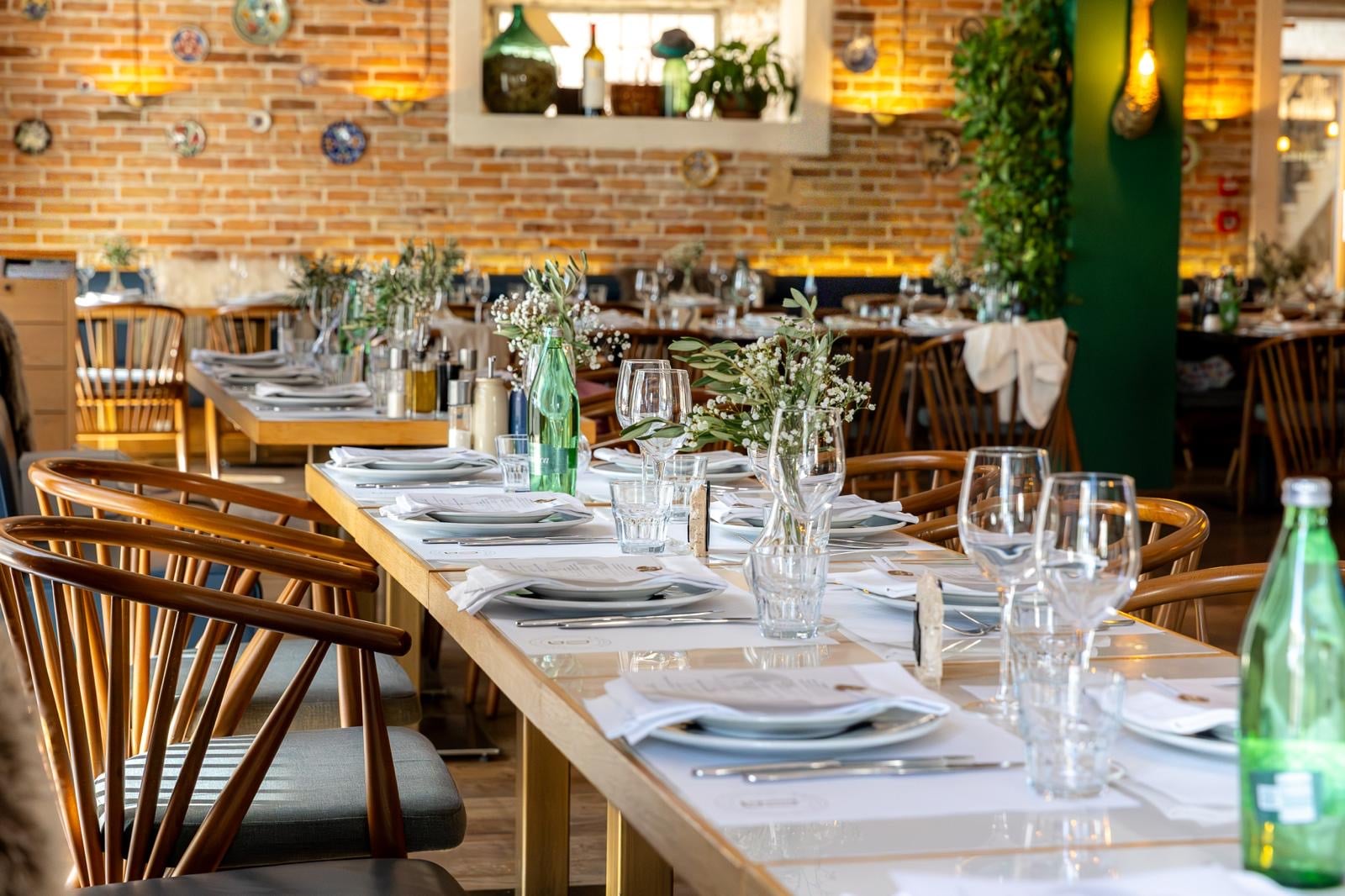 A long Bronzin event table prepared with flowers, menus, linen, and glassware.