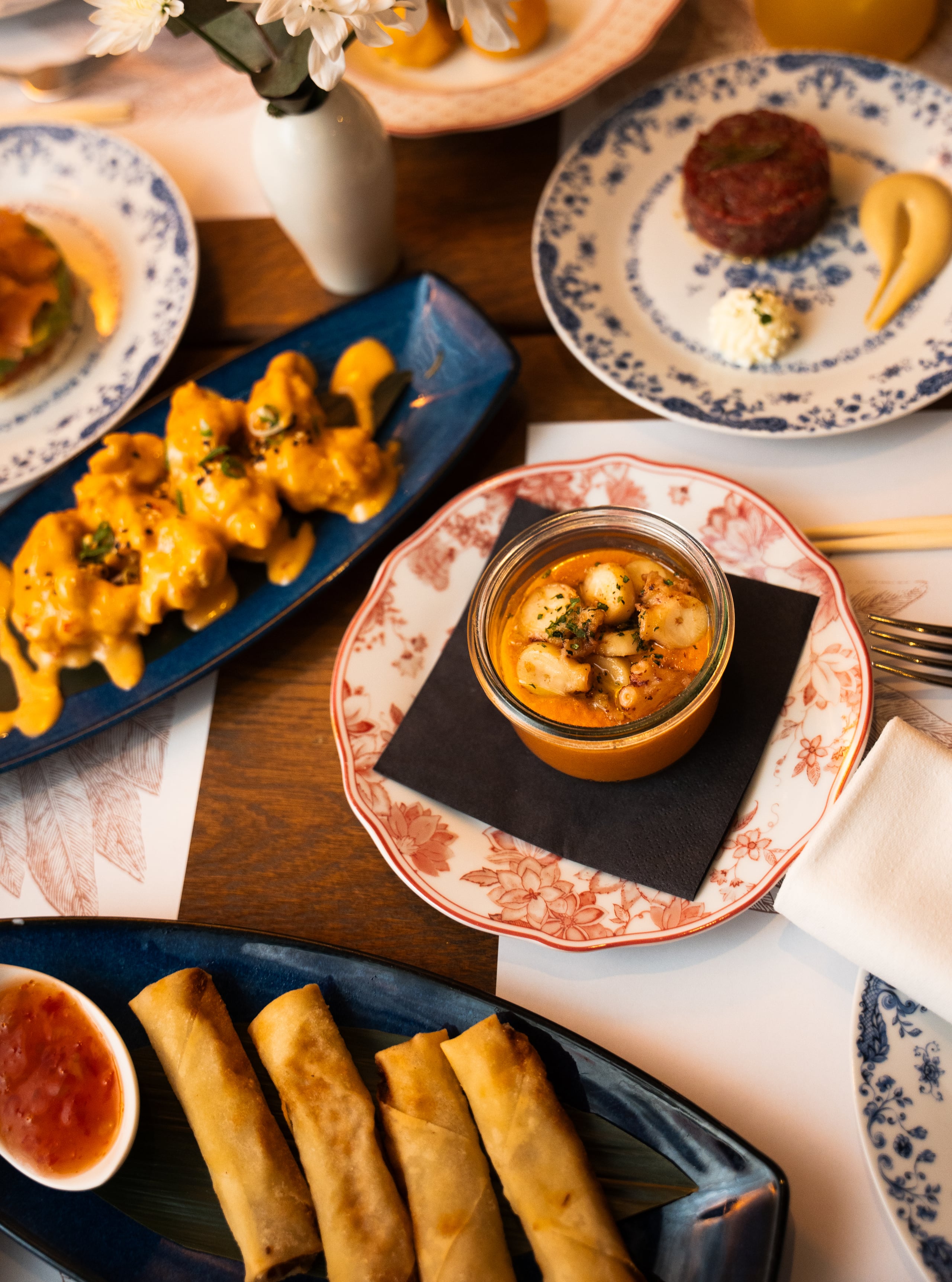 Buta sushi, mezze, cocktails, and shared plates on a dining table.
