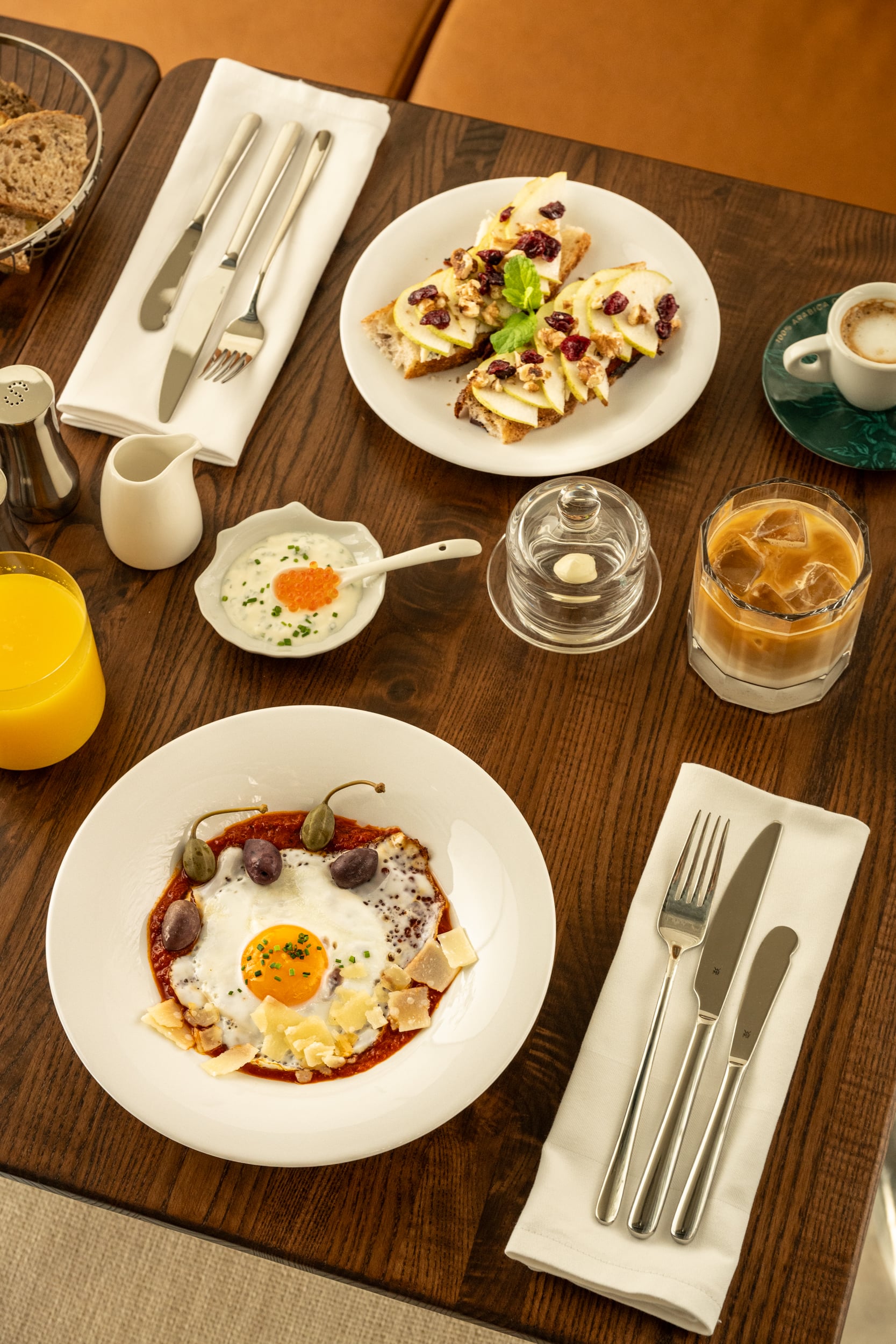 Armerun breakfast dishes, coffee, and orange juice arranged on a dining table.