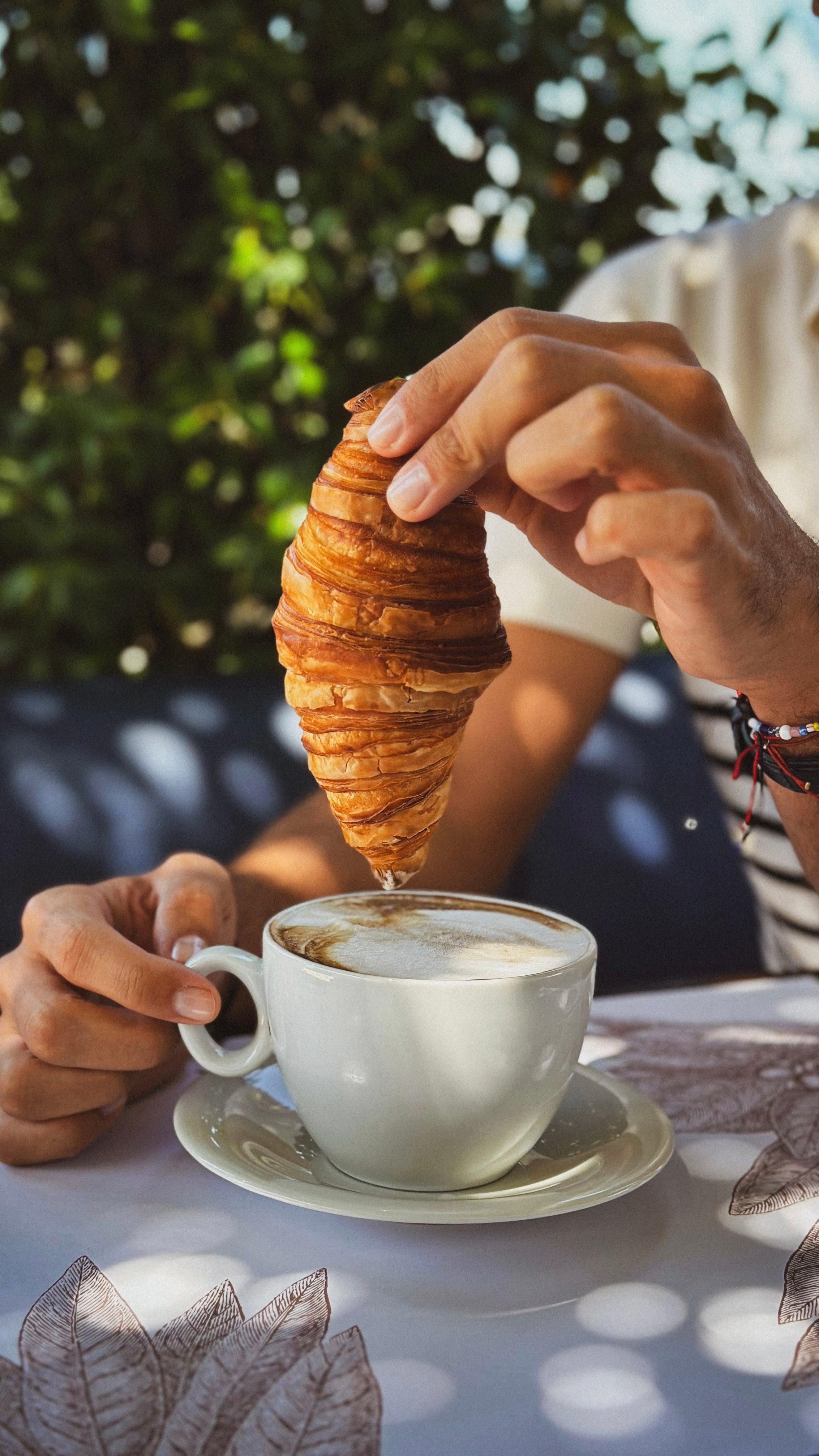 Croissant dipped into coffee at breakfast.